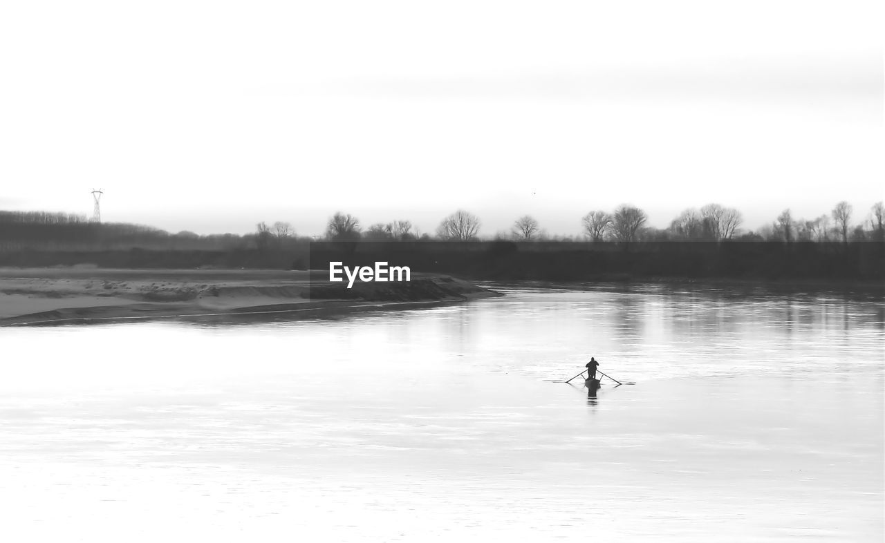 PERSON IN LAKE AGAINST SKY DURING WINTER