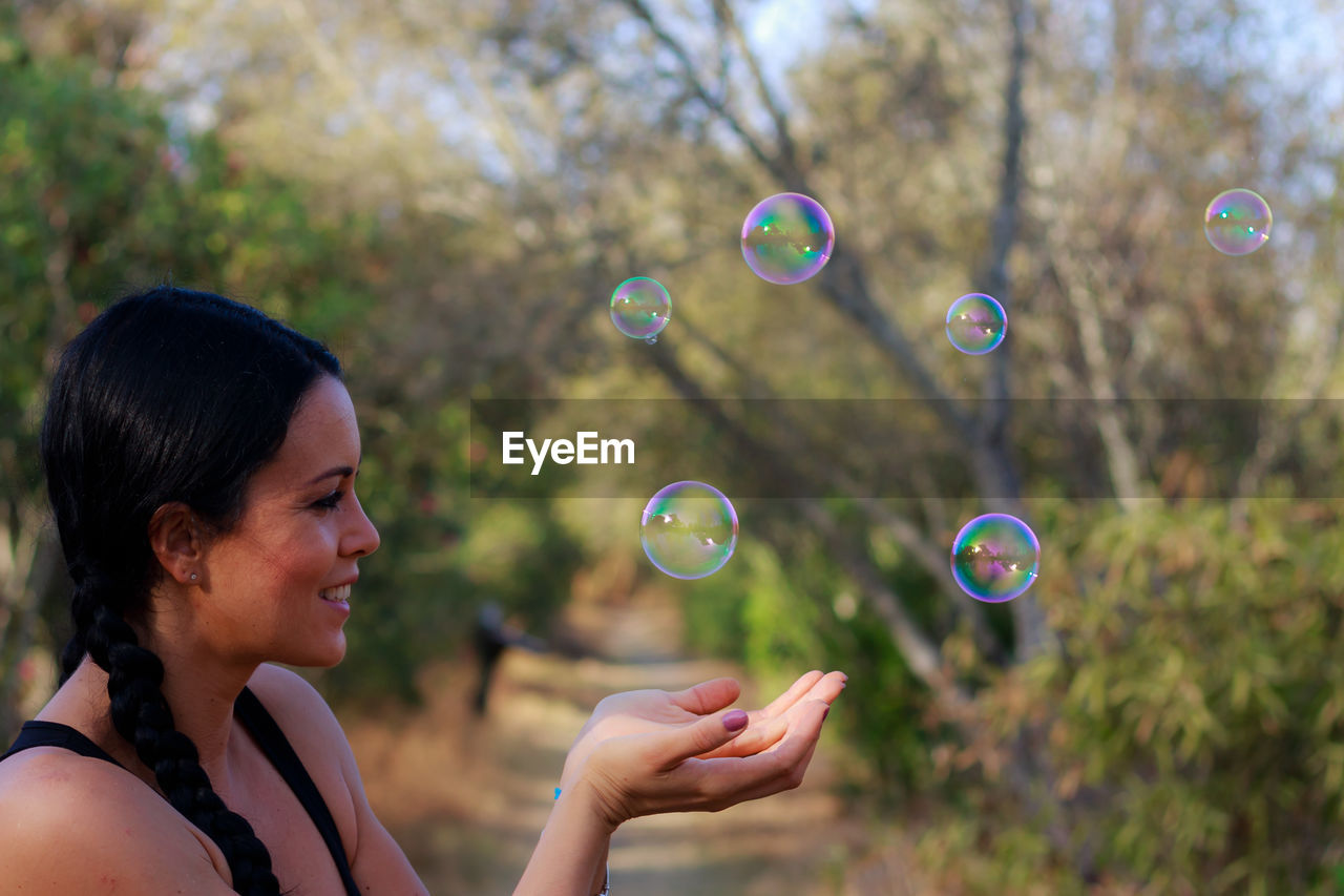 Close-up of smiling woman looking at bubbles
