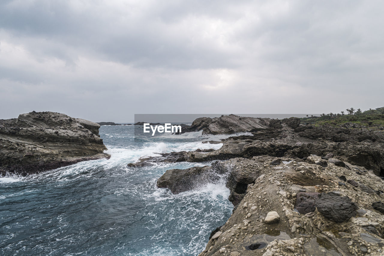 SCENIC VIEW OF ROCKY SHORE AGAINST SKY