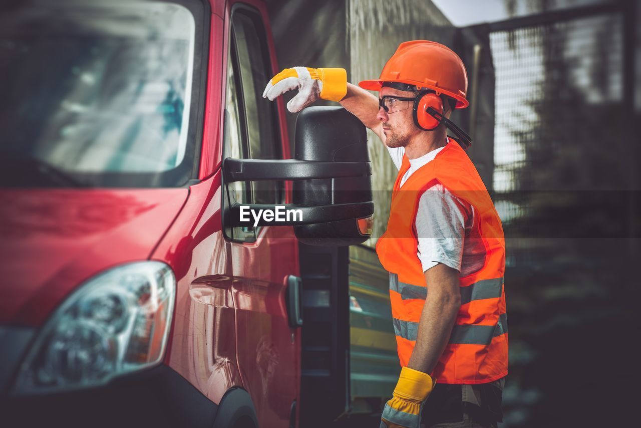 Side view of worker looking away while standing by truck