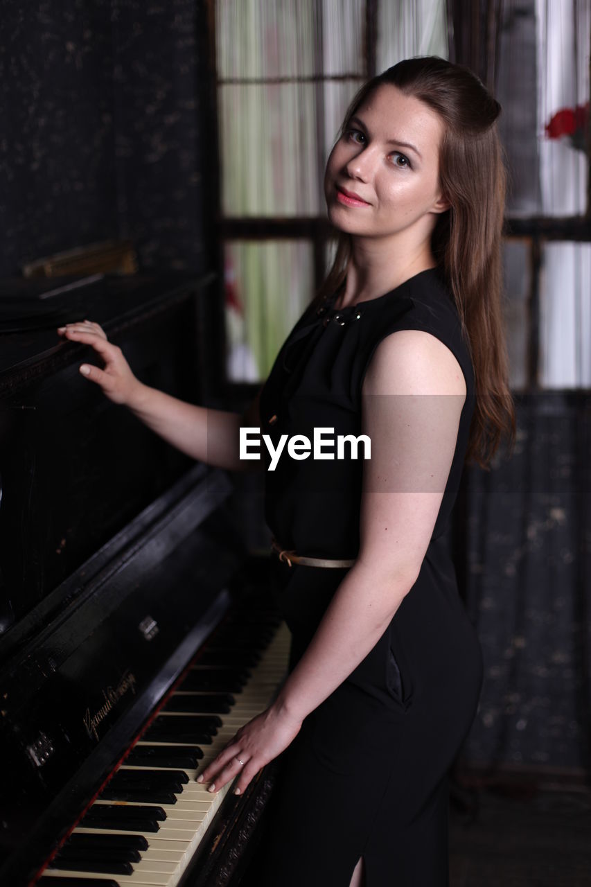 Smiling young woman playing piano