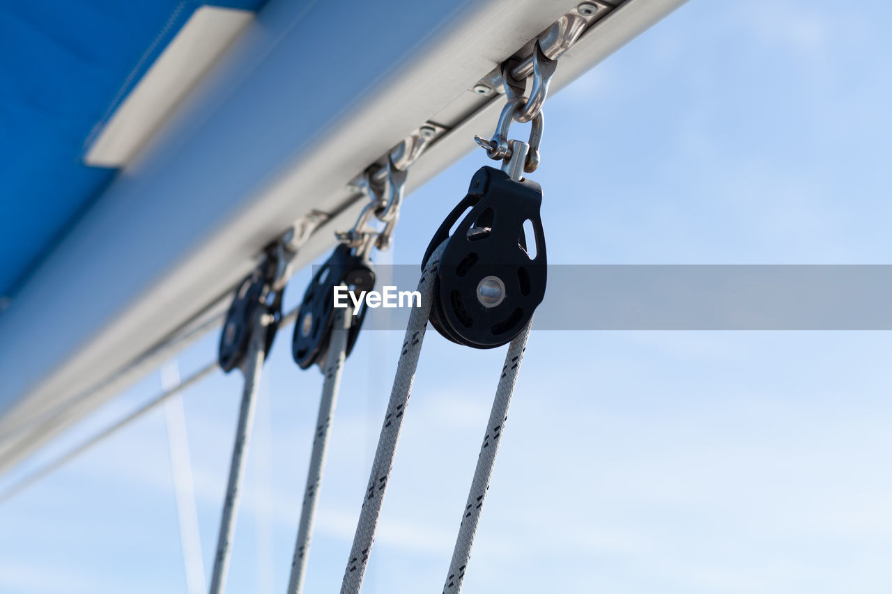 Low angle view of ropes on pulleys against sky