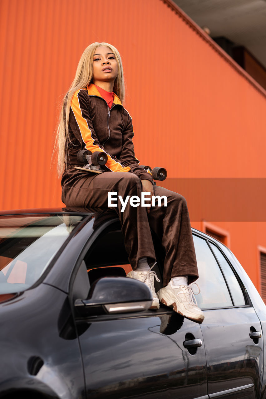 Young african american woman with long blonde hair and sportswear on an orange background