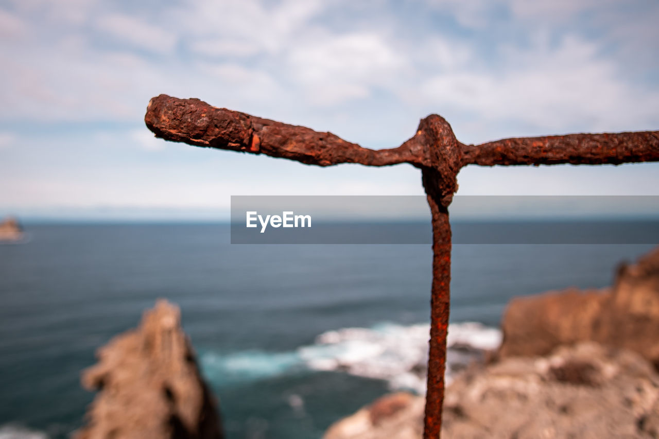 CLOSE-UP OF RUSTY METAL ON BEACH