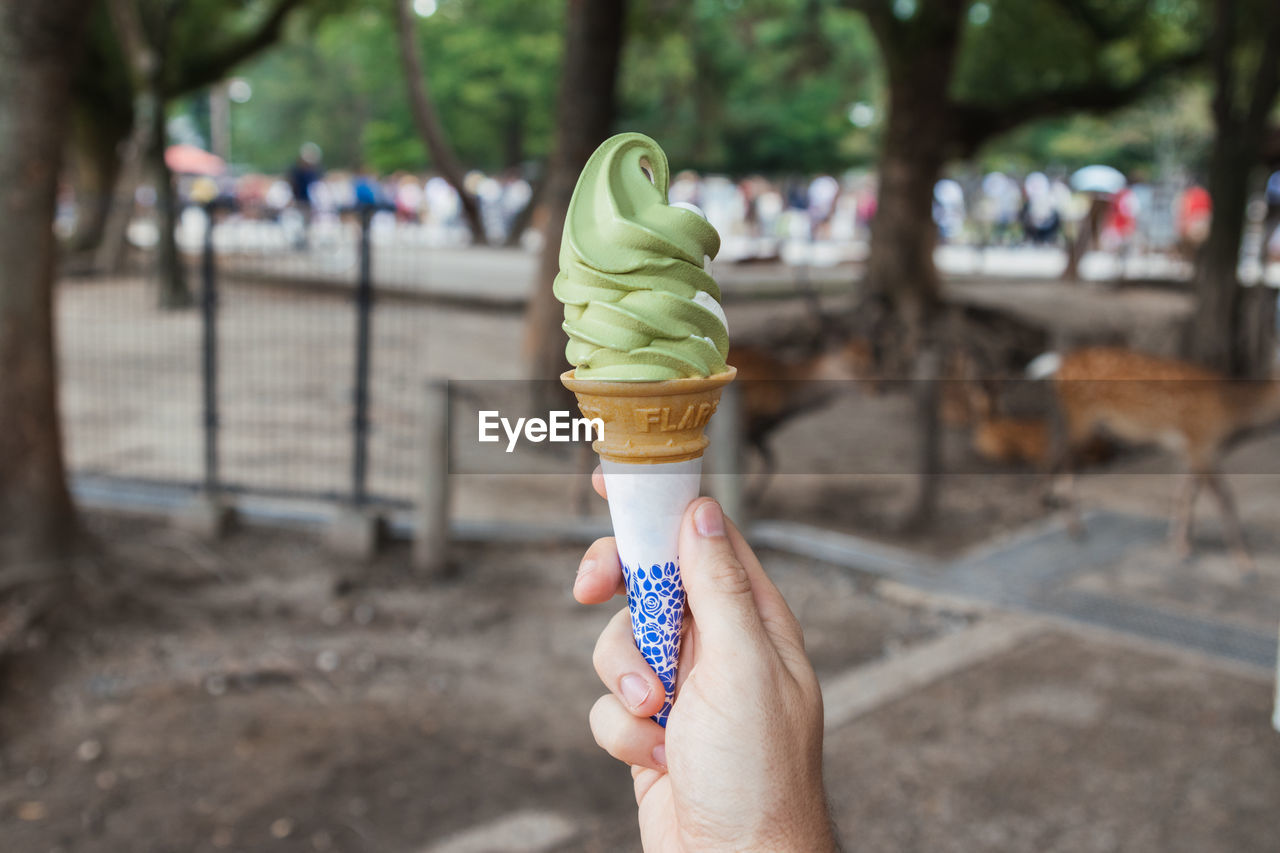 WOMAN HOLDING ICE CREAM CONE ON TABLE