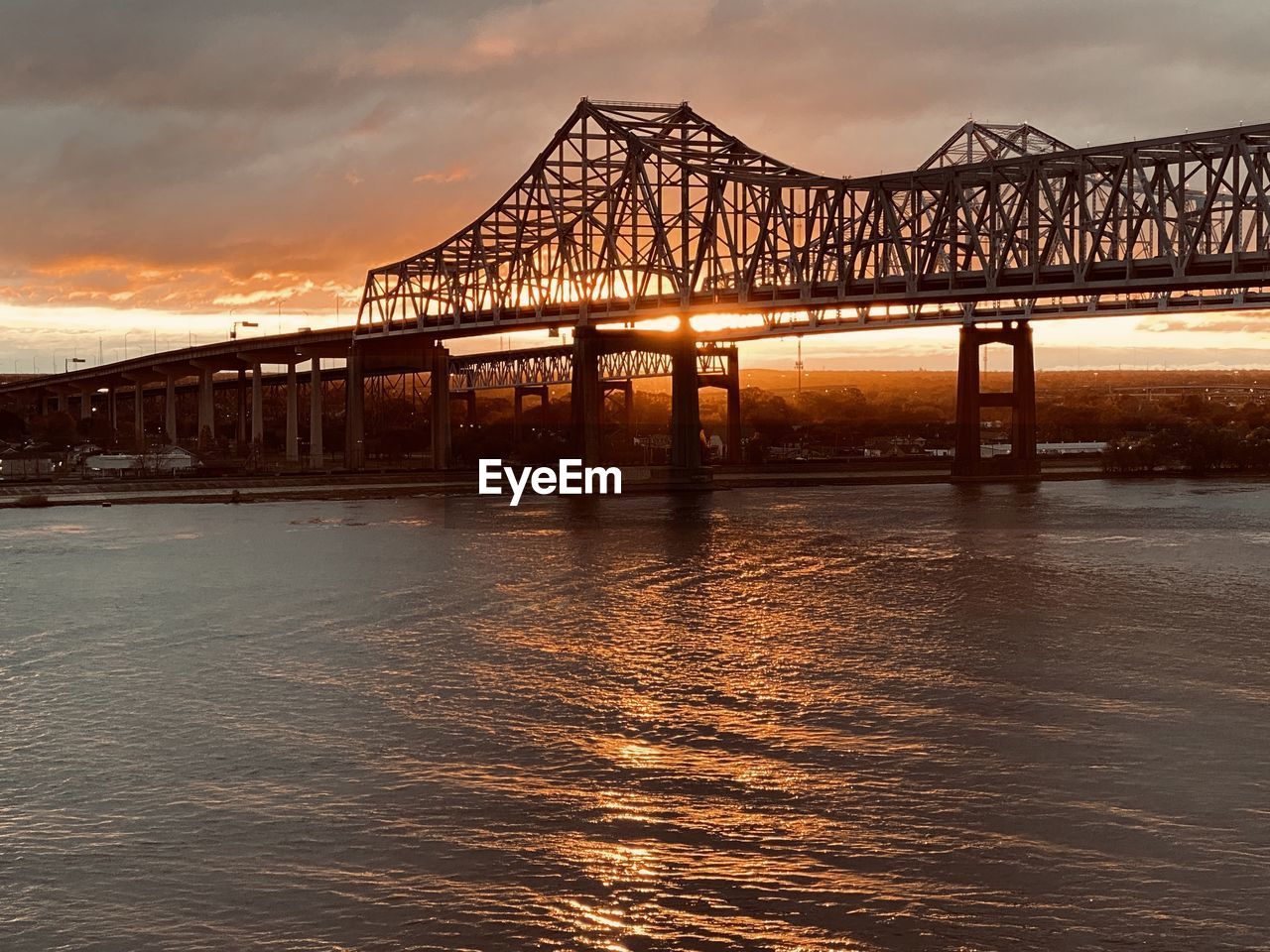 Bridge over river against sky during sunset