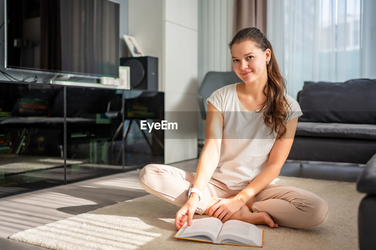 side view of young woman sitting on floor at home