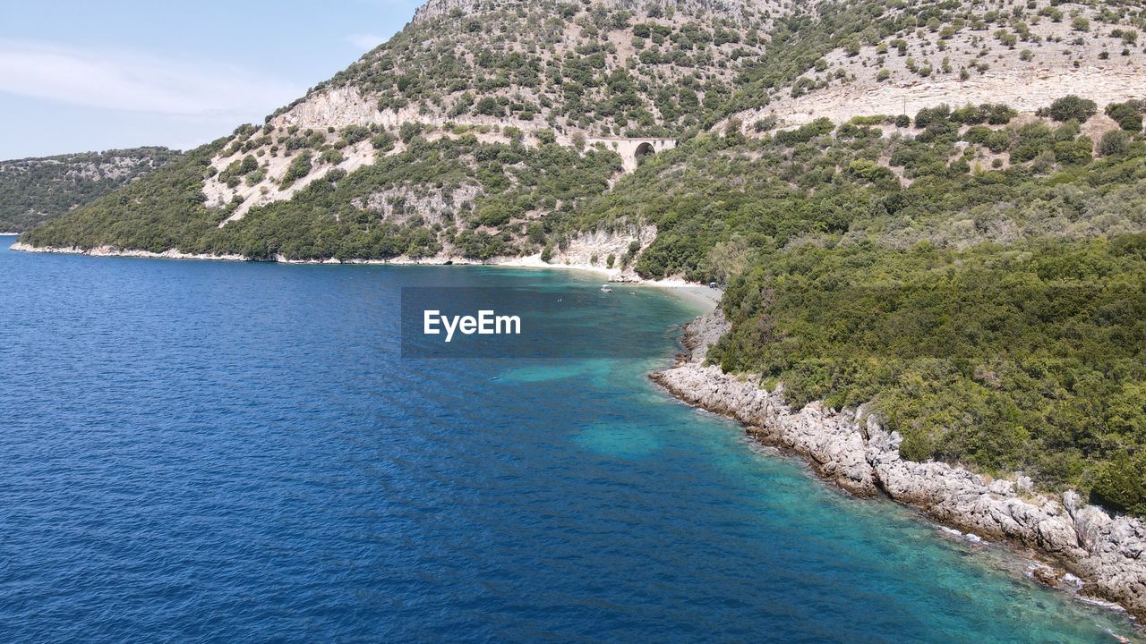 SCENIC VIEW OF SEA AND MOUNTAINS AGAINST BLUE SKY