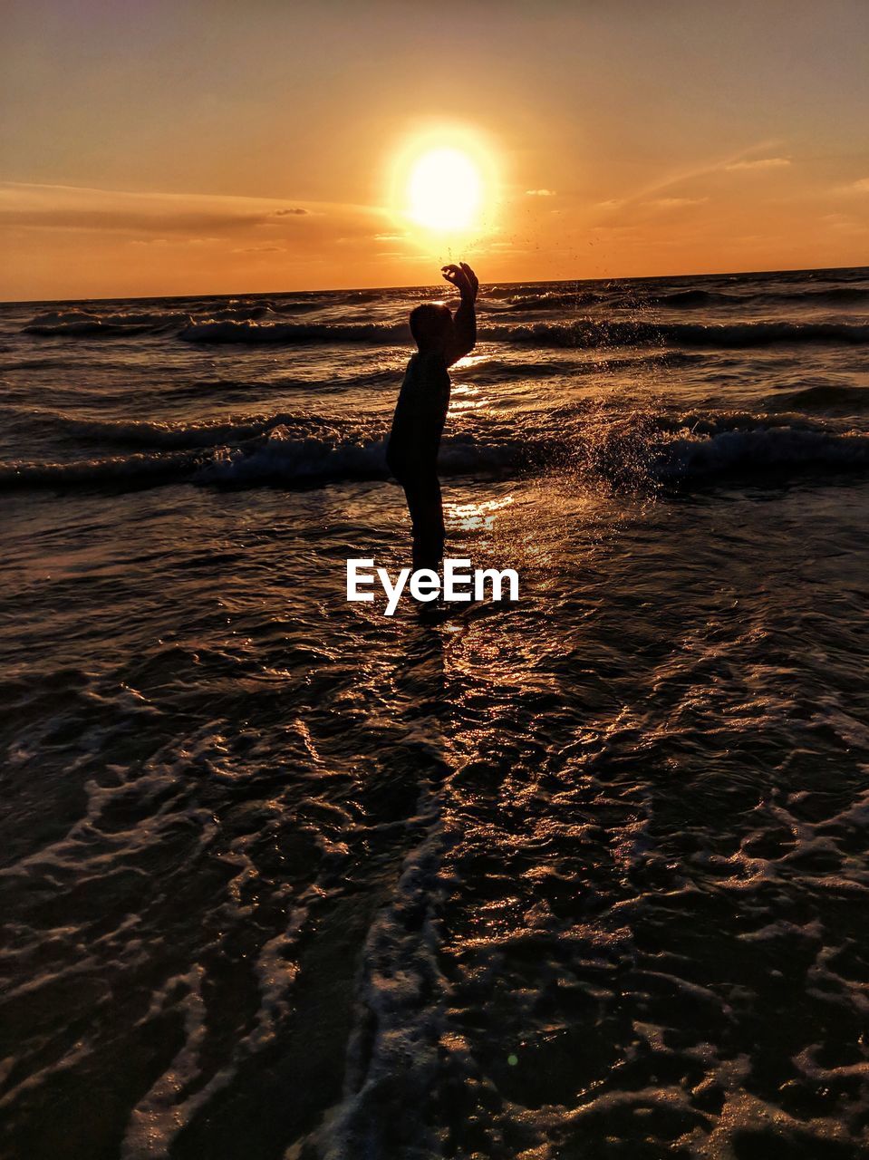 SILHOUETTE PERSON STANDING ON BEACH DURING SUNSET