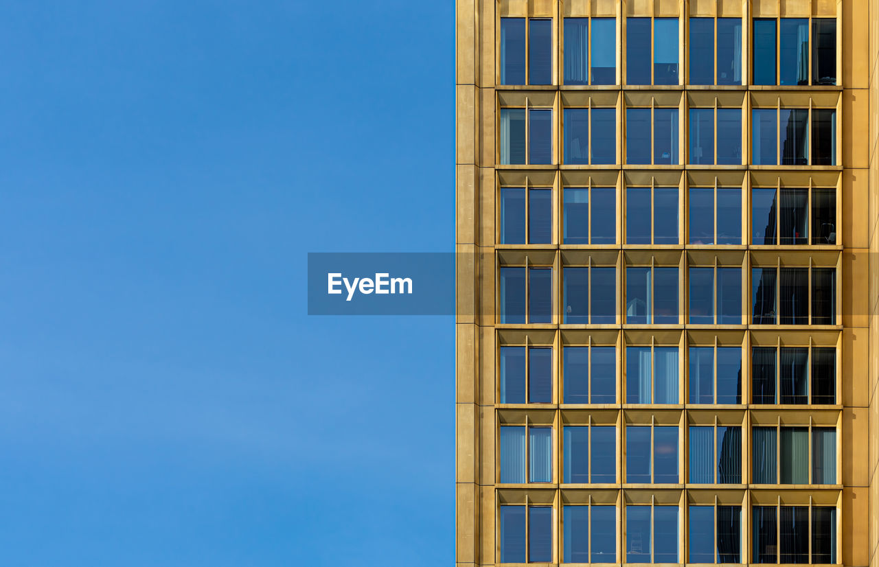 Low angle view of glass building against clear blue sky