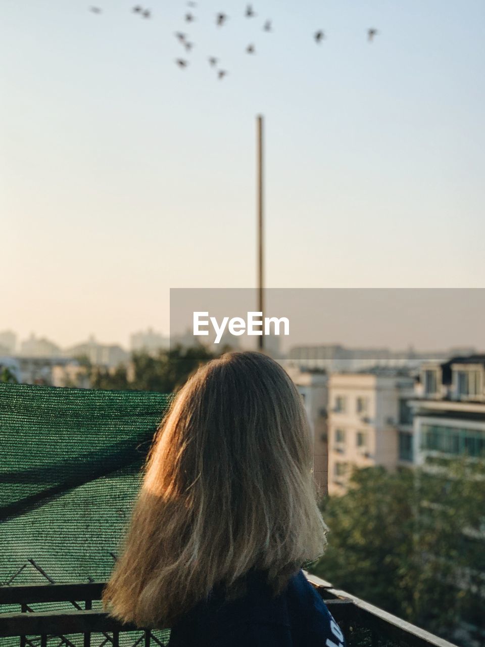 Side view of woman with blond hair in balcony during sunset