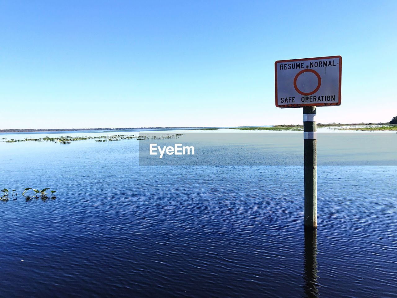 INFORMATION SIGN BY SEA AGAINST CLEAR SKY