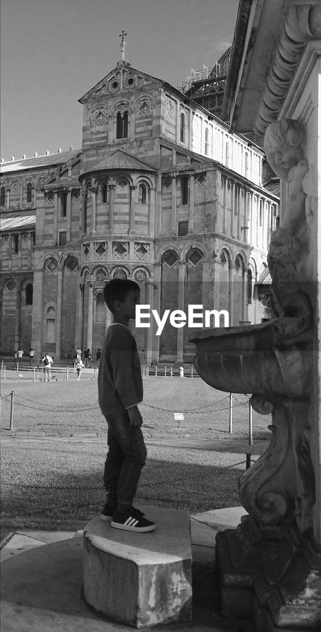 STATUE OF MAN STANDING IN FRONT OF BUILDING