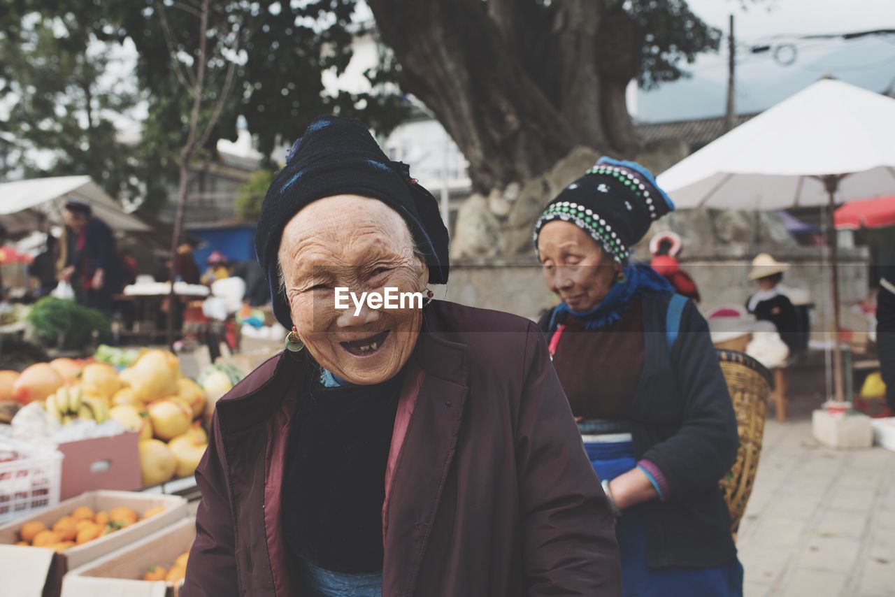 PORTRAIT OF HAPPY FRIENDS SITTING ON MARKET