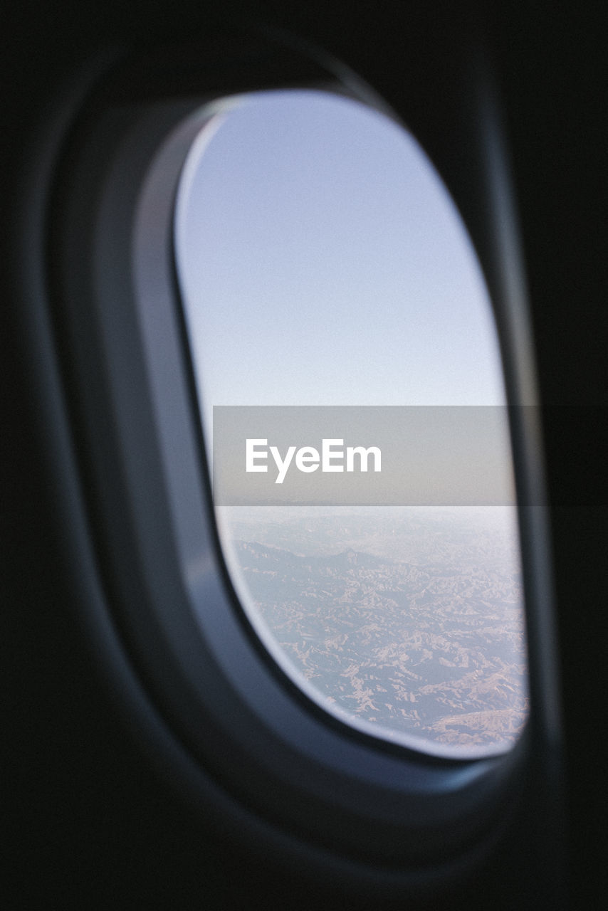 CLOSE-UP OF AIRPLANE WINDOW AGAINST SKY