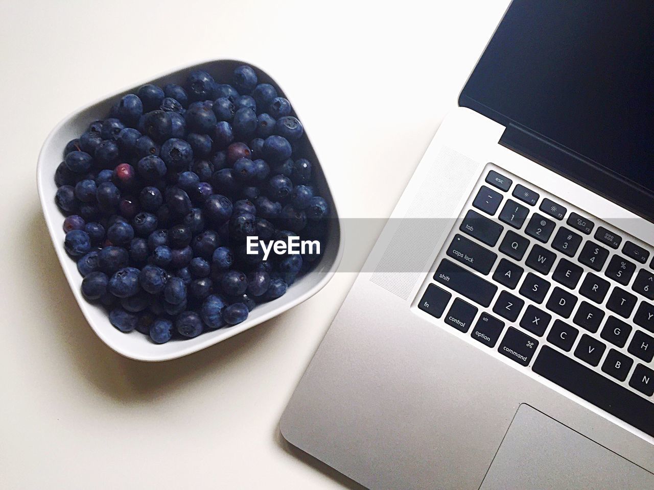 Bowl of blueberries by laptop