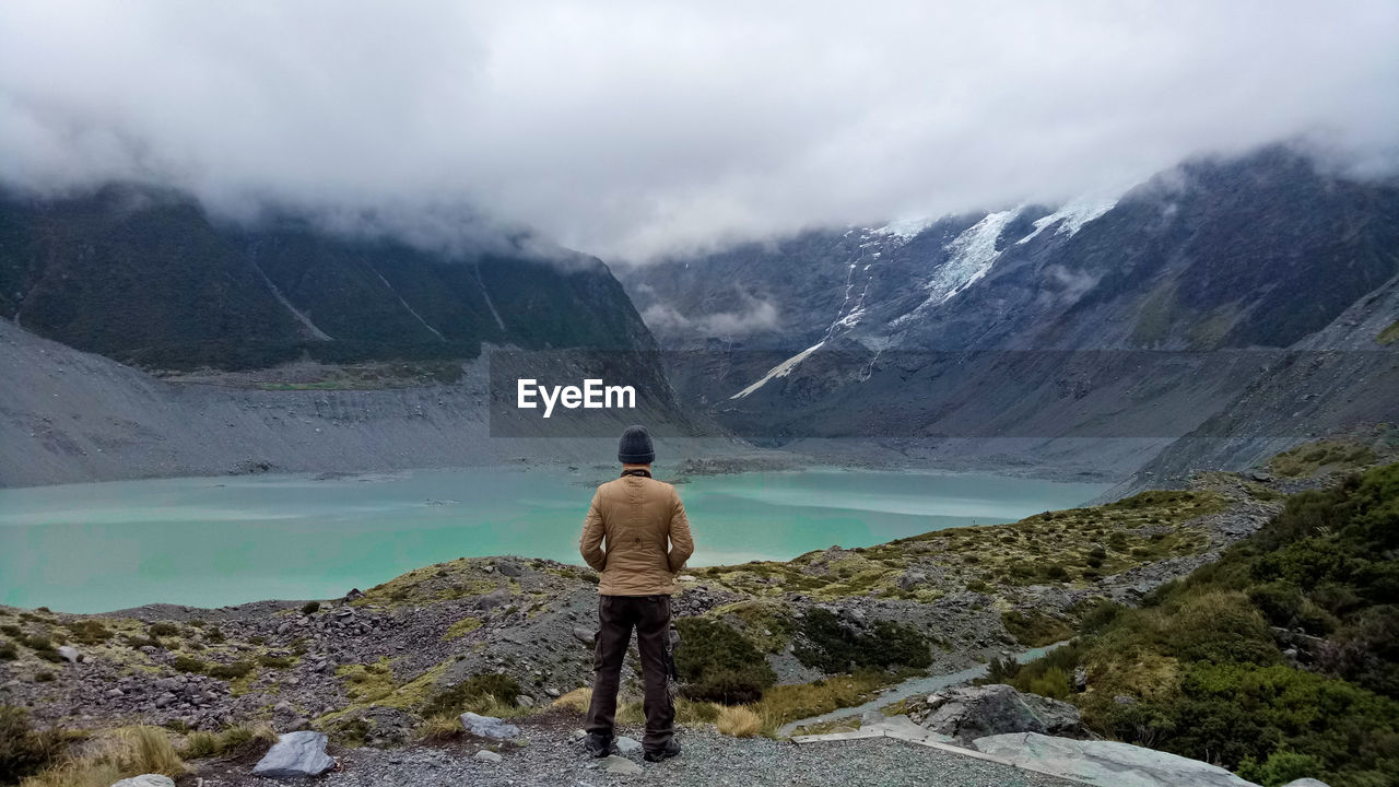 Rear view of woman standing on mountain against sky