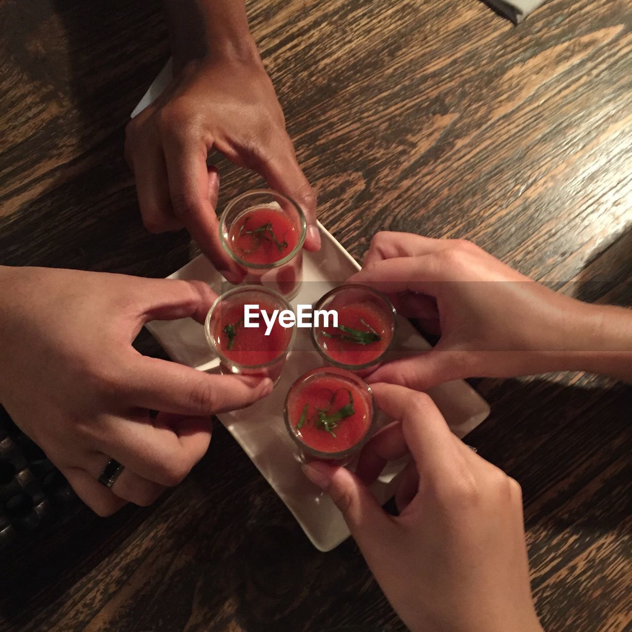 Cropped hands holding drinks in tray on wooden table