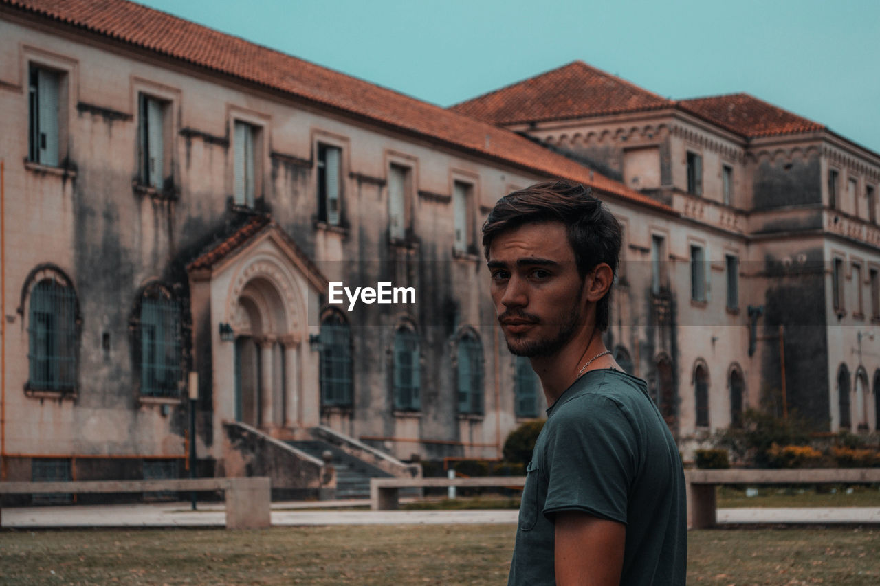 Portrait of young man standing against building