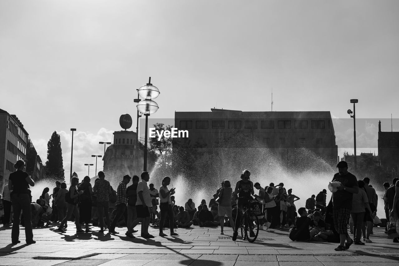 Low angle view of people by water fountain in city