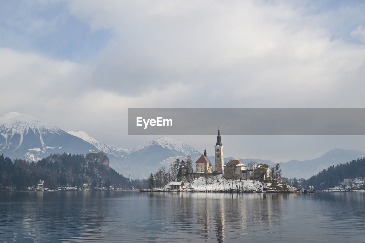 River by church and snowcapped mountains against sky