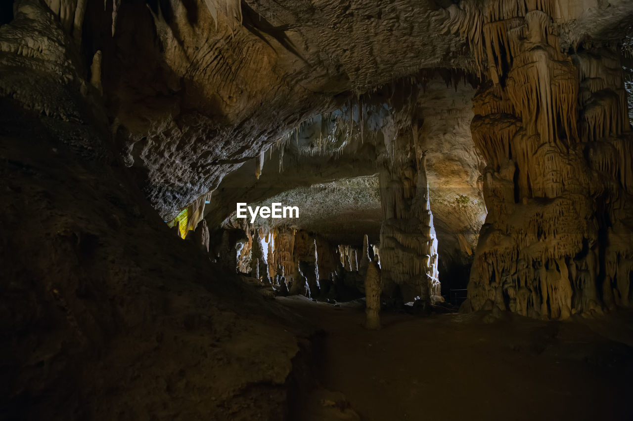 LOW ANGLE VIEW OF ILLUMINATED CAVE AGAINST CLEAR SKY