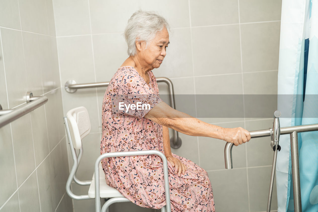 Asian senior or elderly old lady woman patient use toilet bathroom handle security 