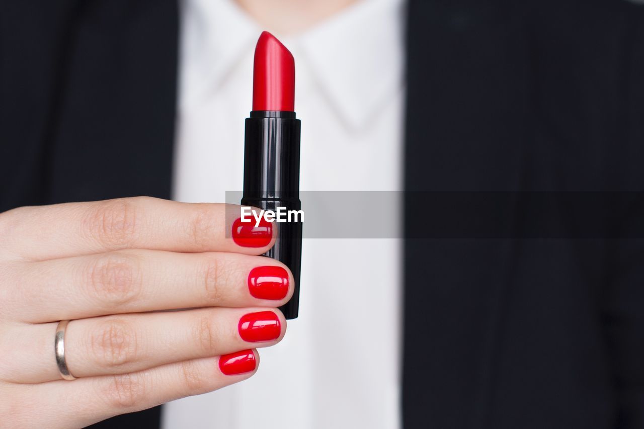 Midsection of woman holding lipstick