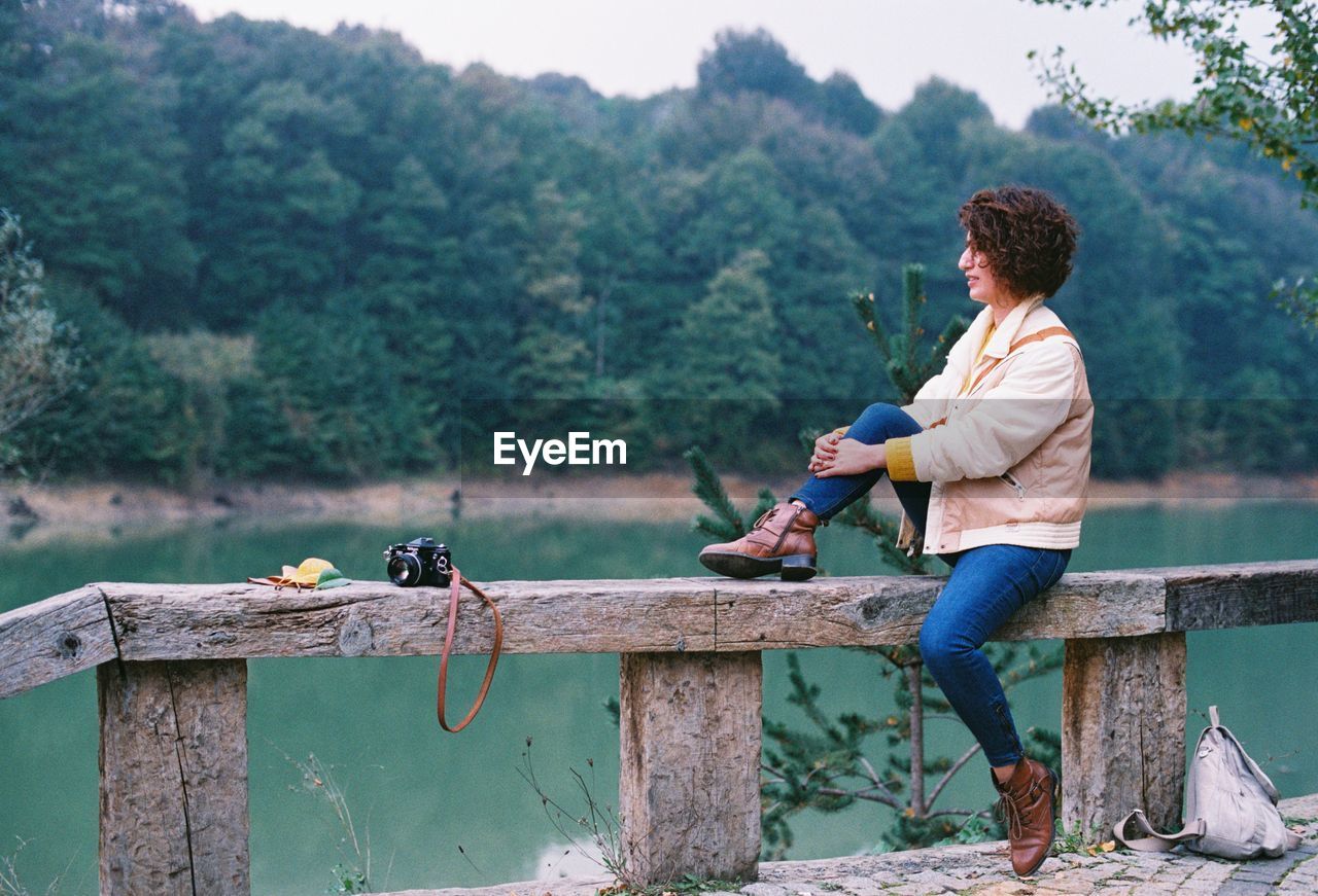 Side view of woman sitting on railing