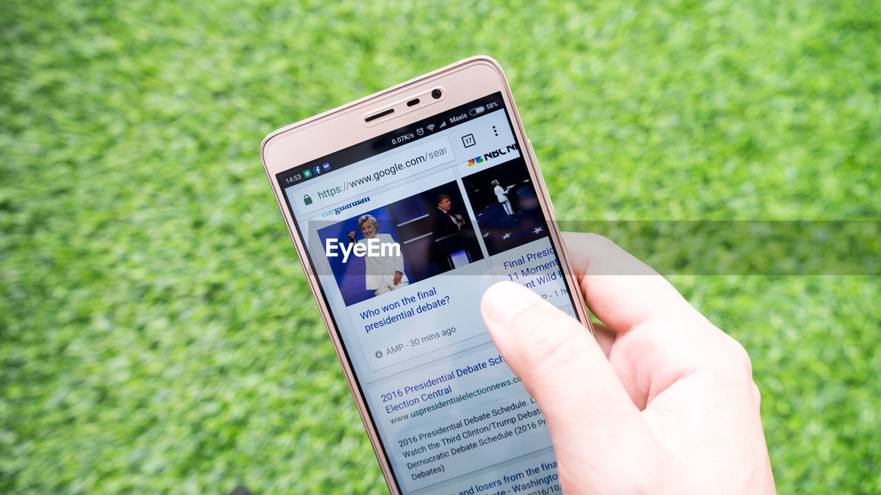 LOW ANGLE VIEW OF PERSON HOLDING BOOK ON GRASSY FIELD