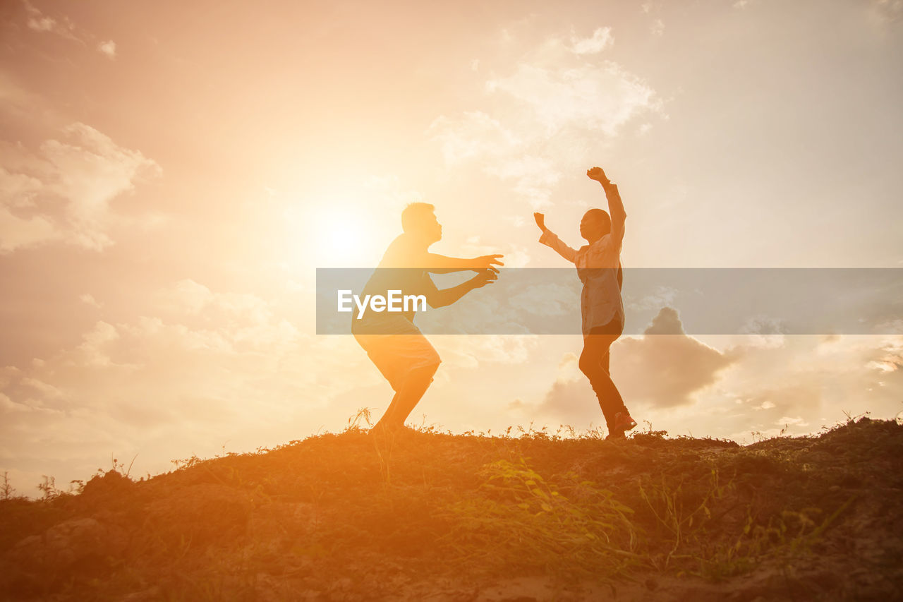 LOW ANGLE VIEW OF FRIENDS STANDING ON LAND AGAINST SKY