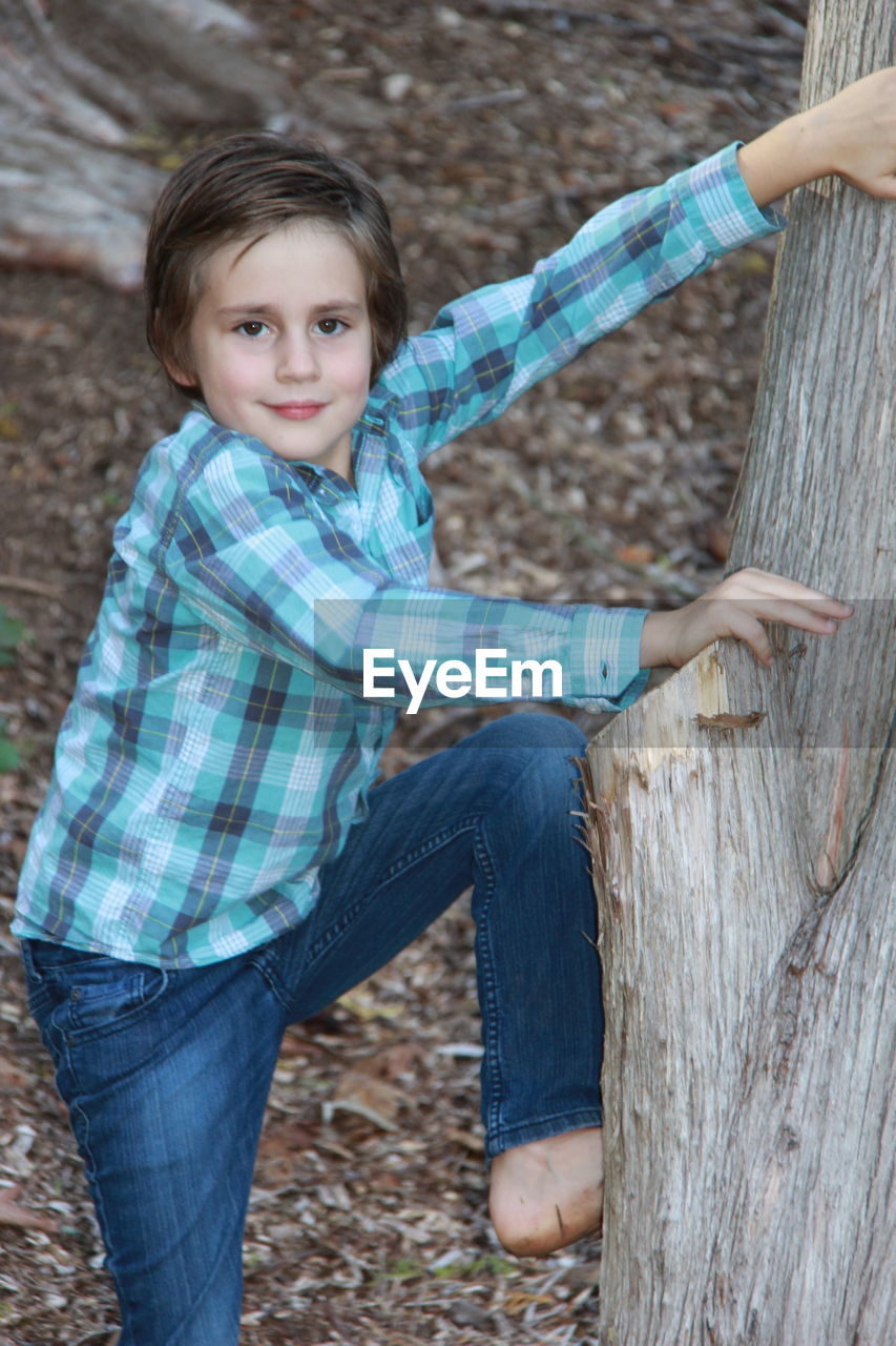 CLOSE-UP PORTRAIT OF BOY HOLDING CAT ON WOOD