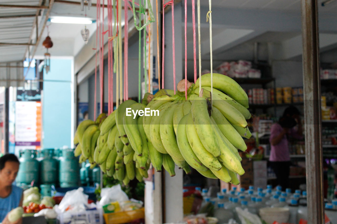 Bananas hanging outside store at market for sale