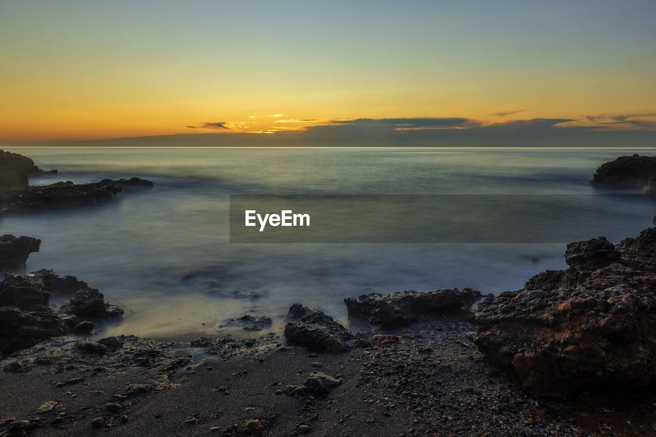 SCENIC VIEW OF BEACH AGAINST SKY DURING SUNSET