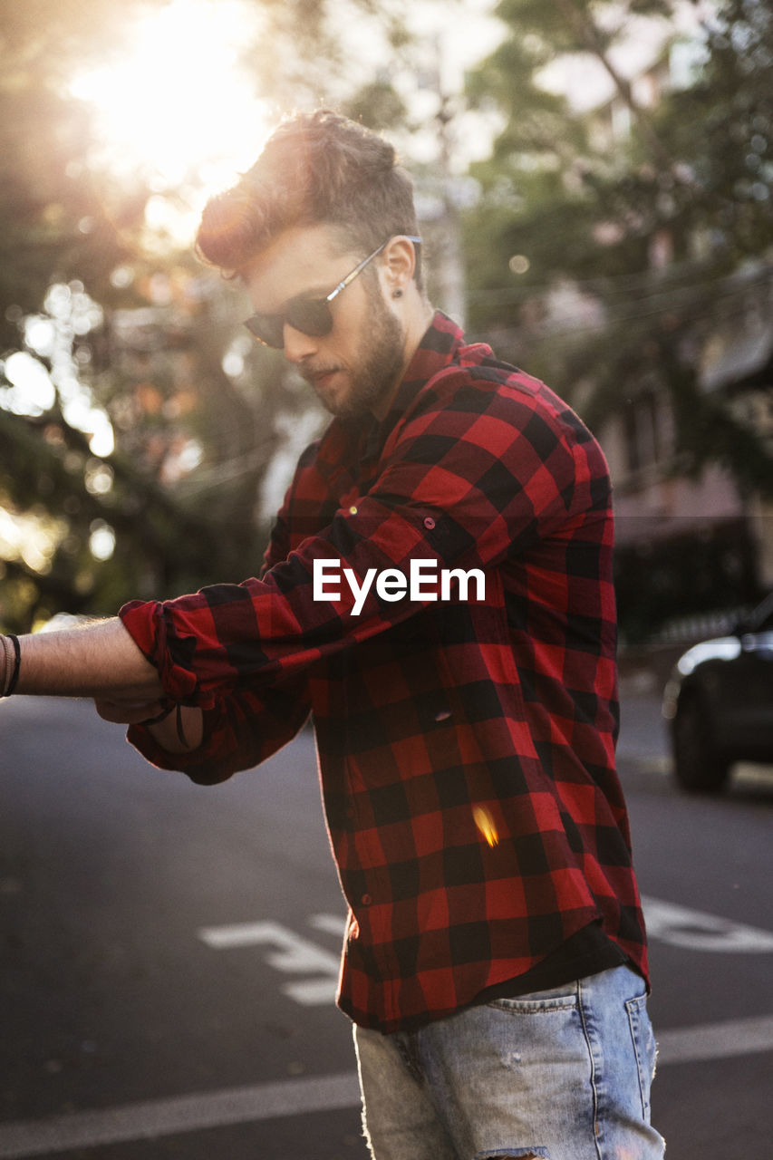 Man wearing plaid shirt and sunglasses while standing on road