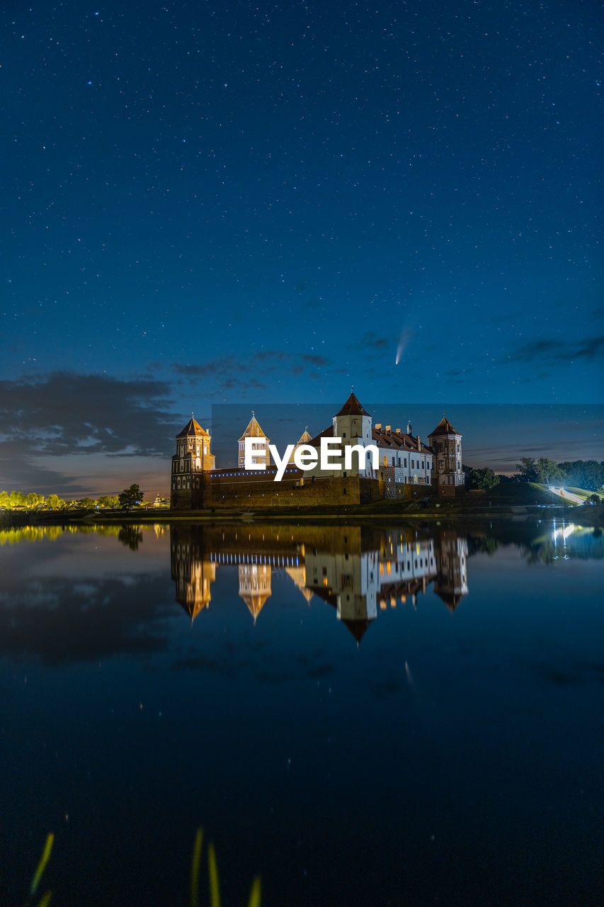 Comet neowise in a night landscape. mir castle in belarus.