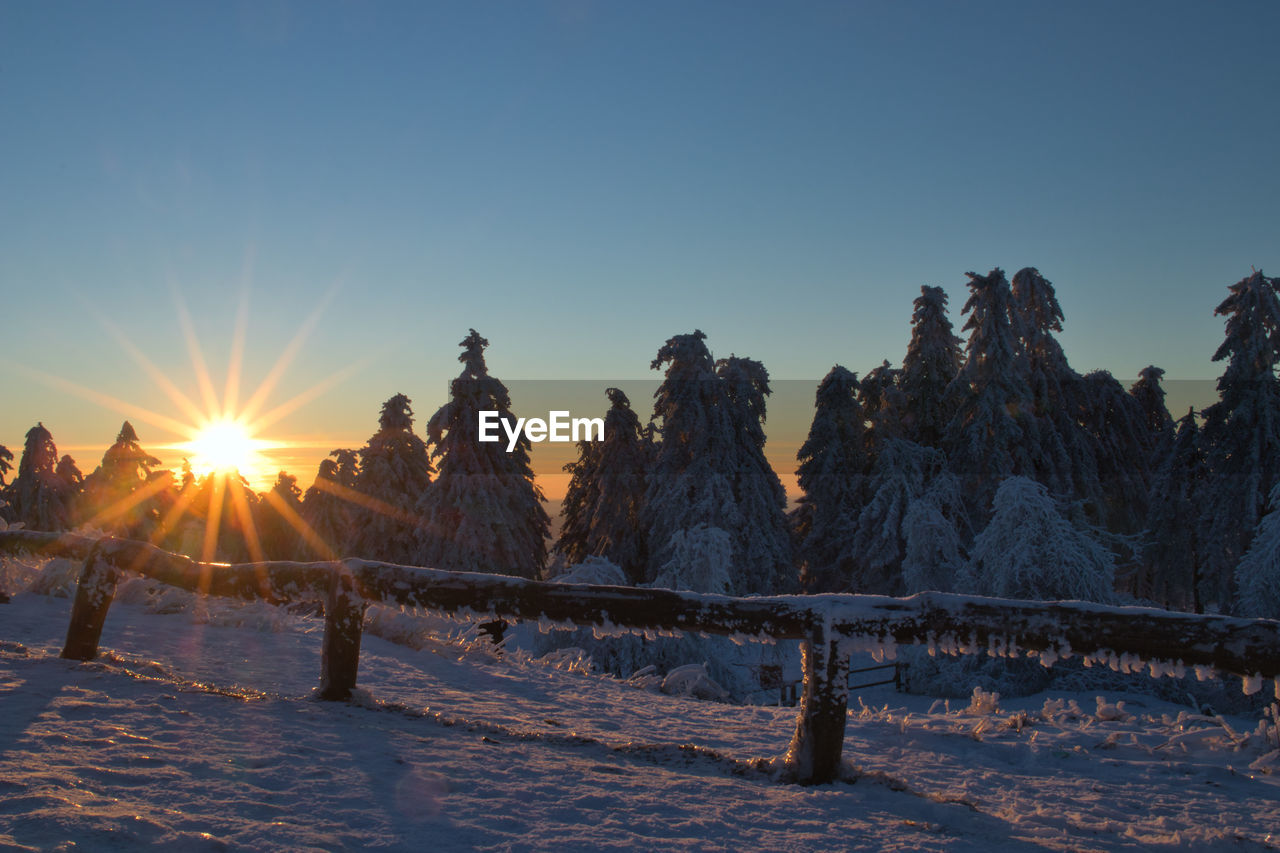 SCENIC VIEW OF SNOWCAPPED FIELD AGAINST SKY DURING SUNSET