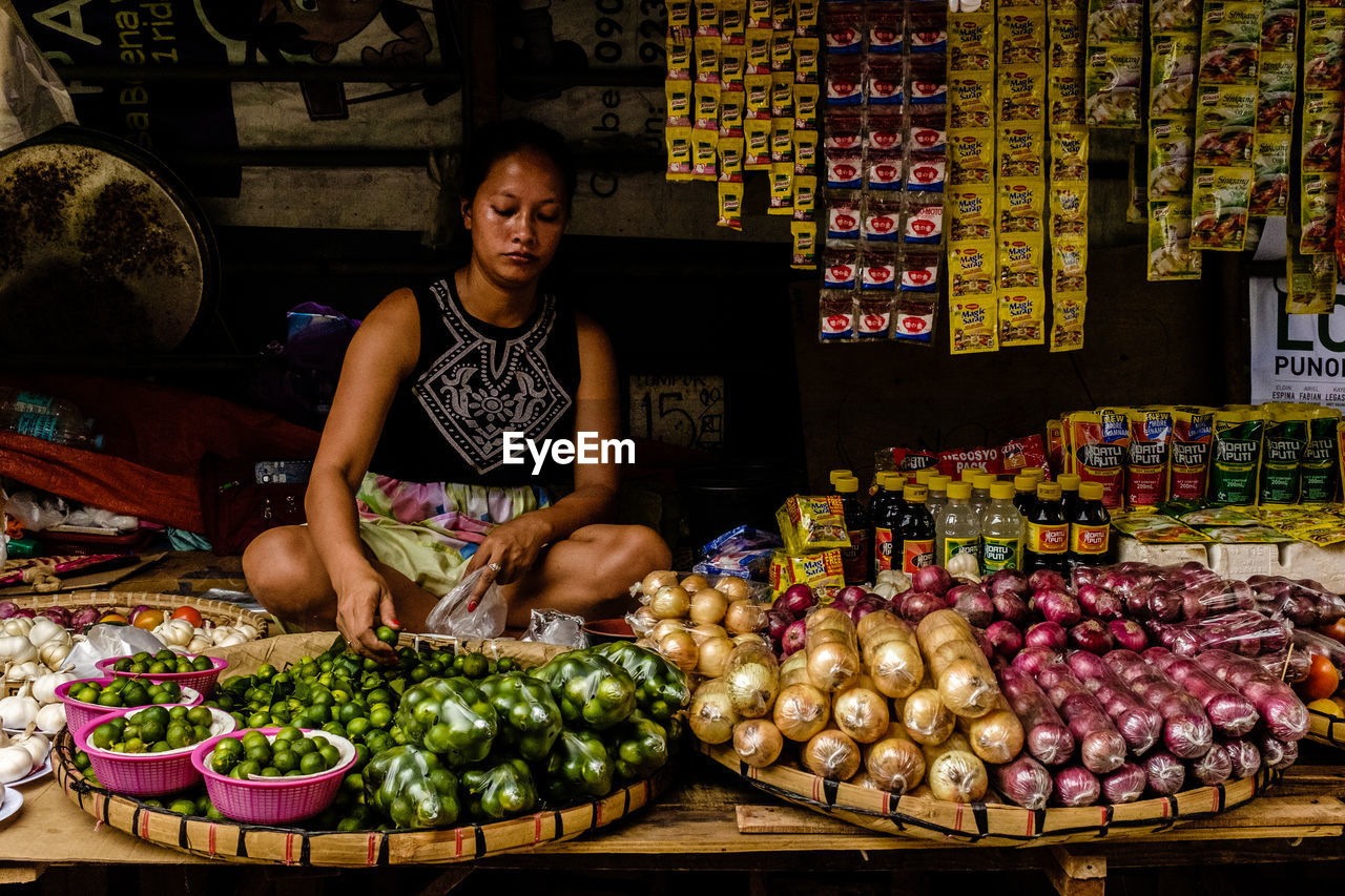 WOMAN WITH VEGETABLES FOR SALE AT MARKET