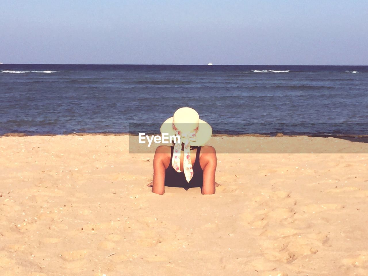 Woman lying on beach against sky