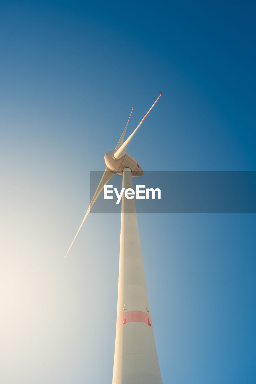 LOW ANGLE VIEW OF WIND TURBINE AGAINST BLUE SKY