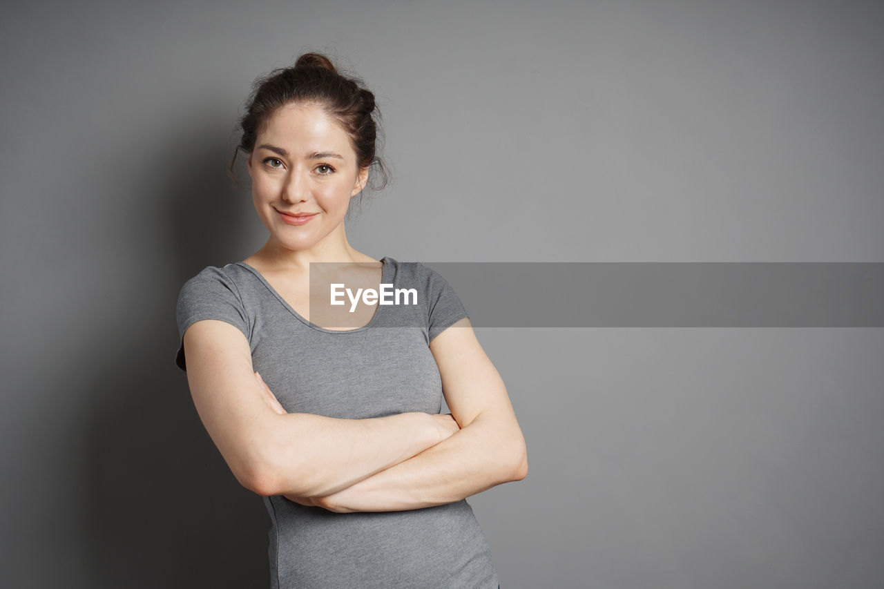 Portrait of smiling young woman against gray background