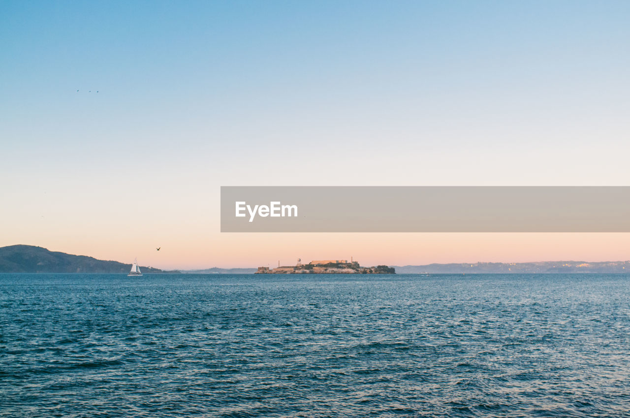 Distant view of alcatraz island in sea against clear sky