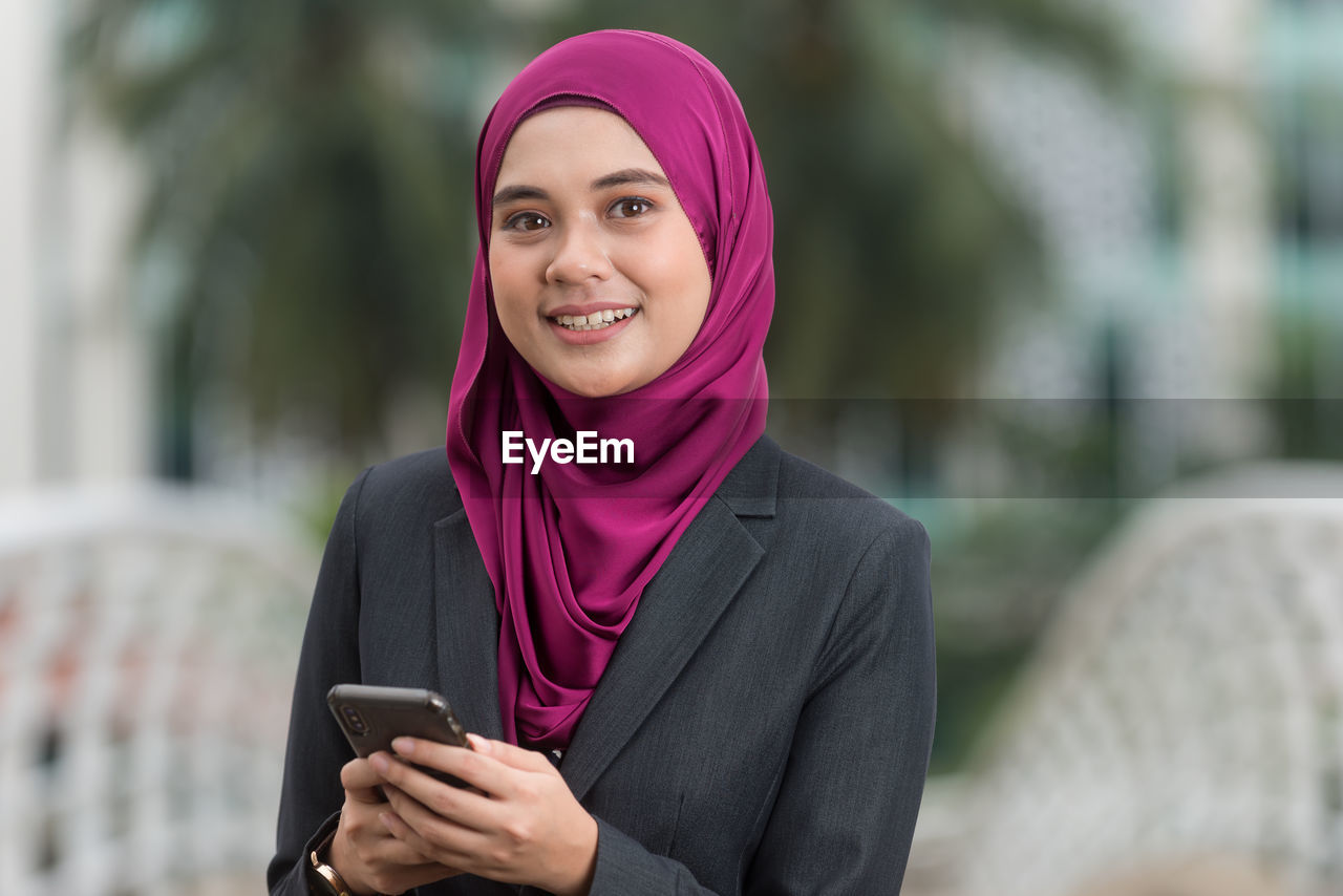 Young businesswoman wearing hijab using smart phone