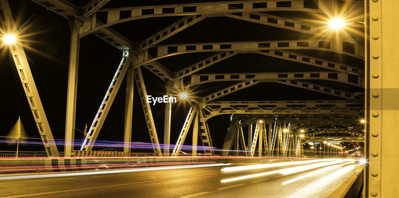 Light trails on bridge over street at night