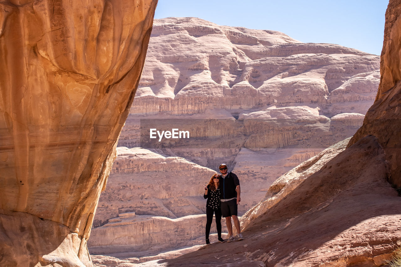 REAR VIEW OF MAN STANDING ON ROCK FORMATION