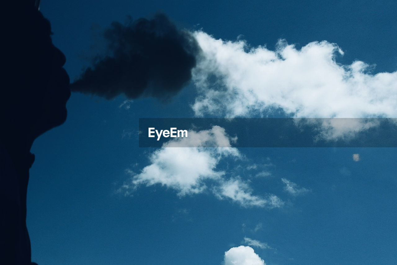 Low angle view of man smoking against sky