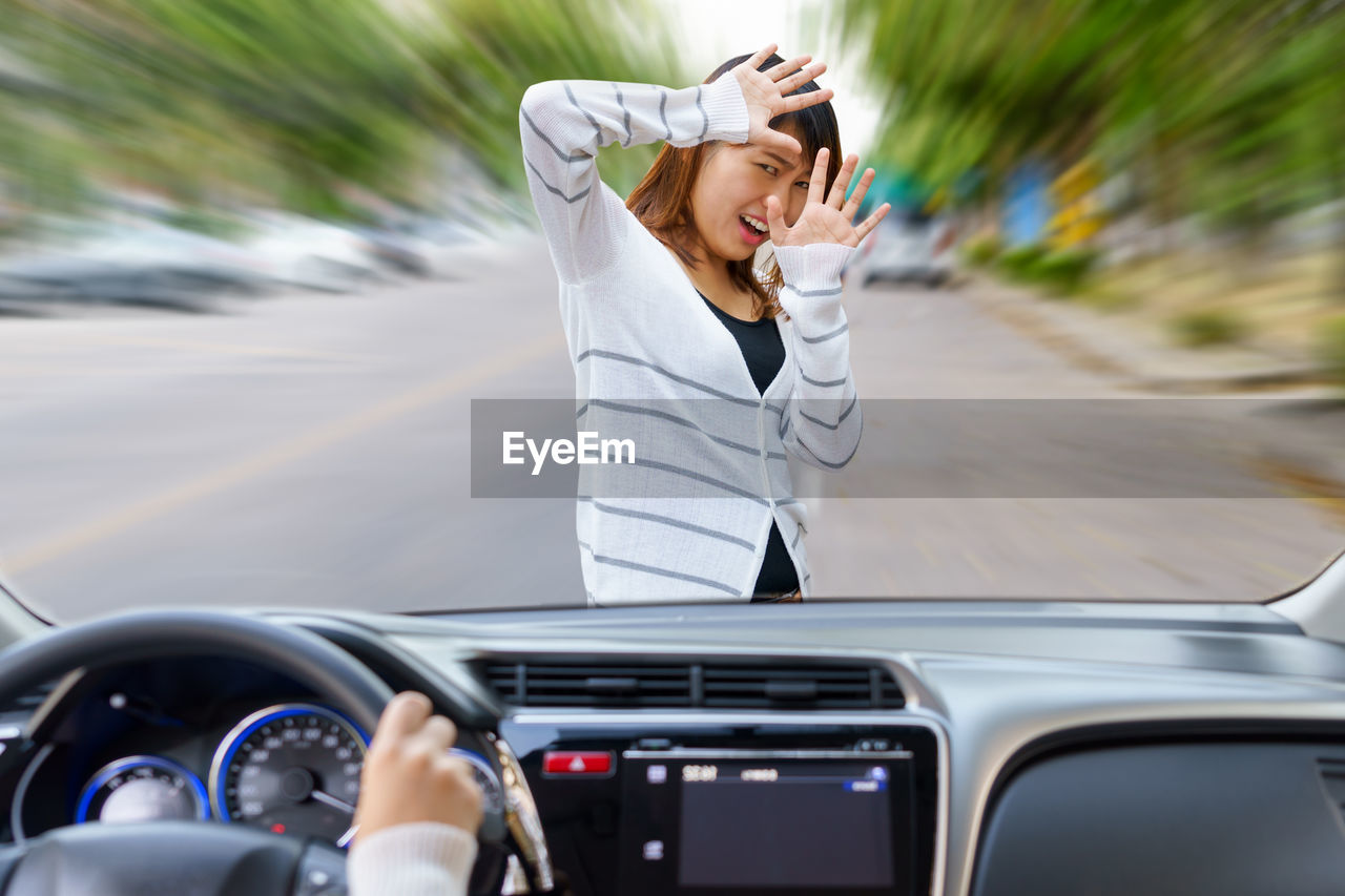 Scared woman in front of car seen through windshield