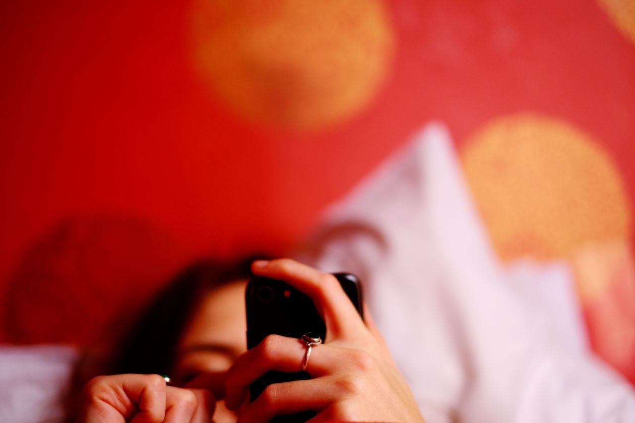 Woman using mobile phone while lying on bed at home