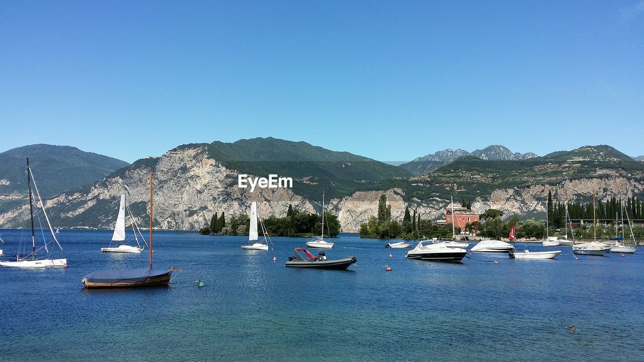 BOATS MOORED ON SEA AGAINST CLEAR BLUE SKY