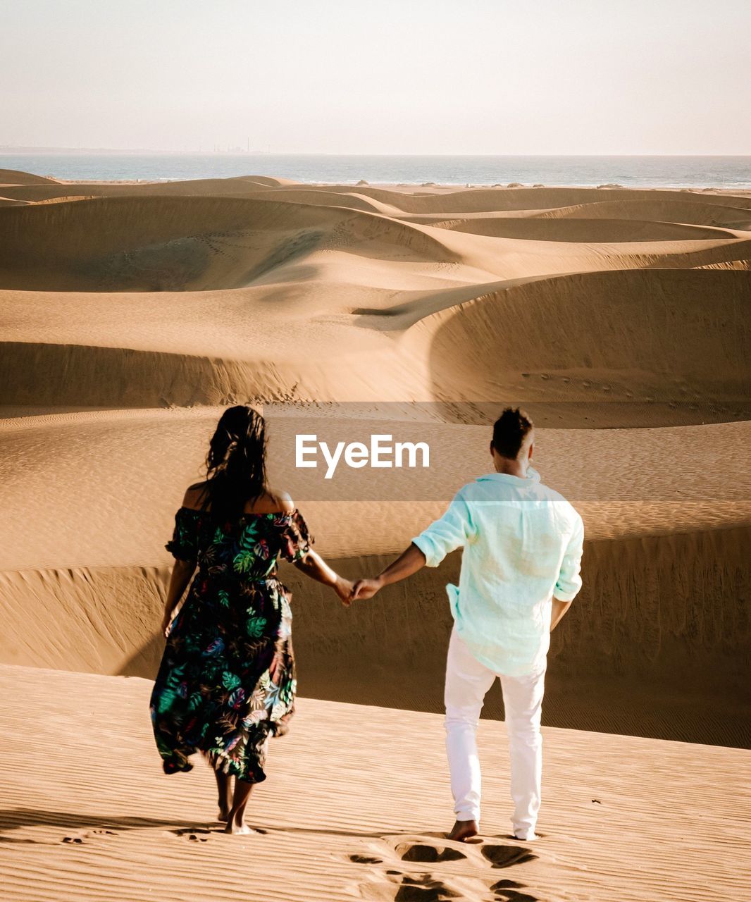 FULL LENGTH REAR VIEW OF PEOPLE WALKING ON SAND